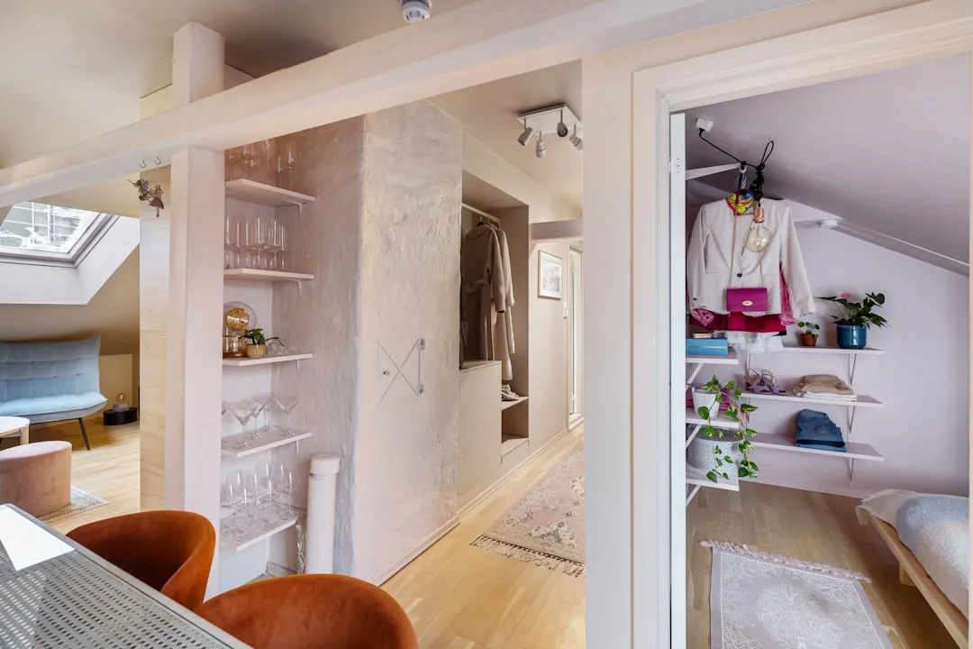 Open-plan attic apartment zoned with built-in shelving, walk-in closet nook, and defined living areas without walls