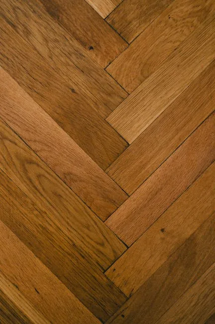 Herringbone hardwood floor pattern in warm brown oak showing diagonal plank installation typical of premium flooring