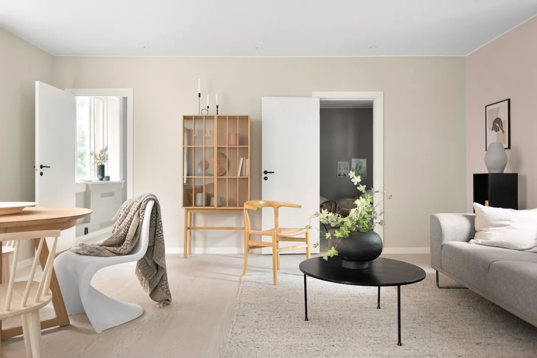 Scandinavian living room with soft beige walls, grey sofa, black round coffee table, and warm wood furniture accents