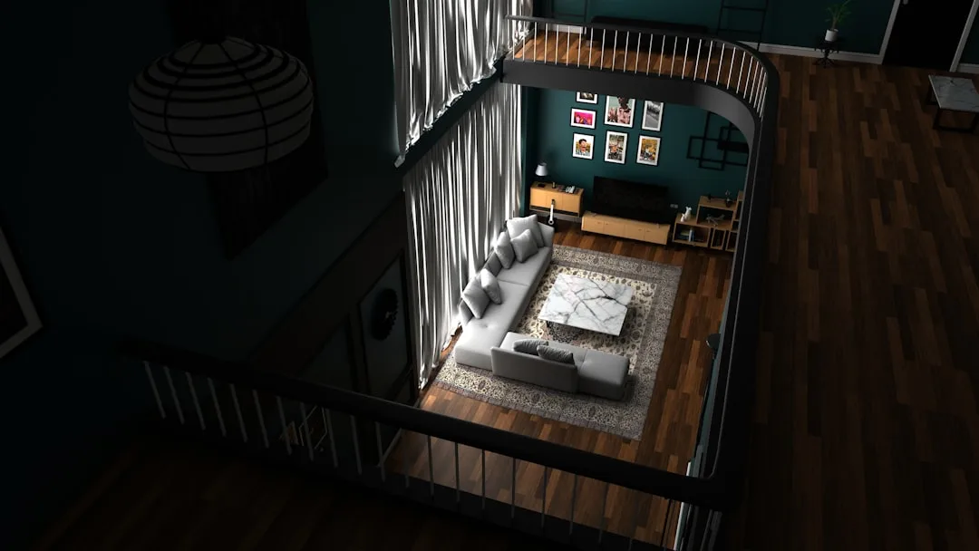 Aerial view of loft living room with dark hardwood flooring, white sectional sofa, and teal accent wall with gallery fra