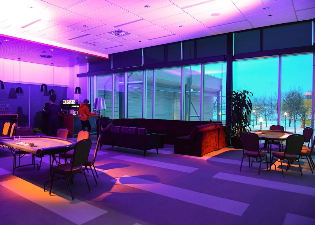 Open-plan casino lounge with mixed purple and warm amber accent lighting zones across seating and gaming areas