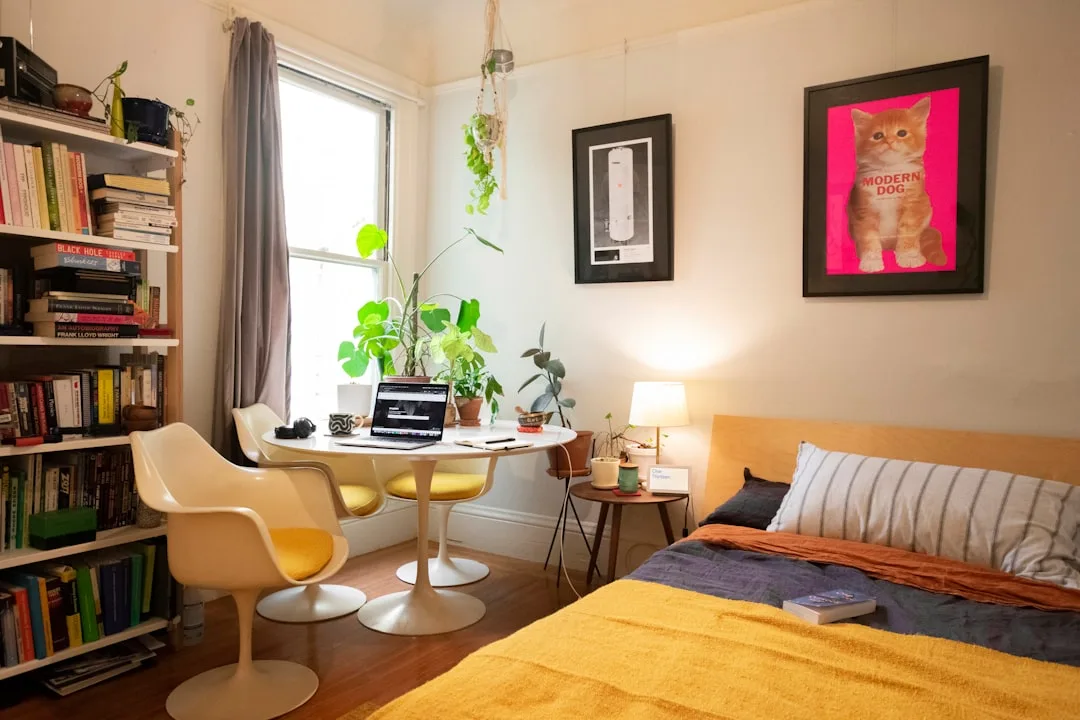 Small bedroom under 120 sq ft with tulip table workspace, bookshelf, and bed showing multi-functional furniture arrangem
