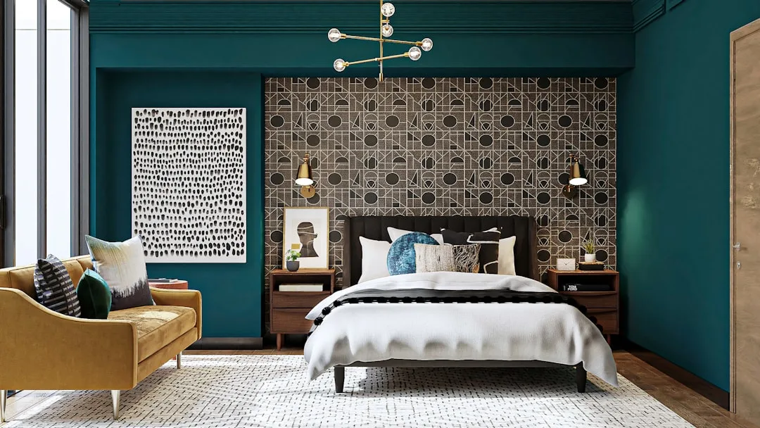 Mid-century modern bedroom with teal walls, geometric wallpaper accent, mustard sofa, and brass chandelier