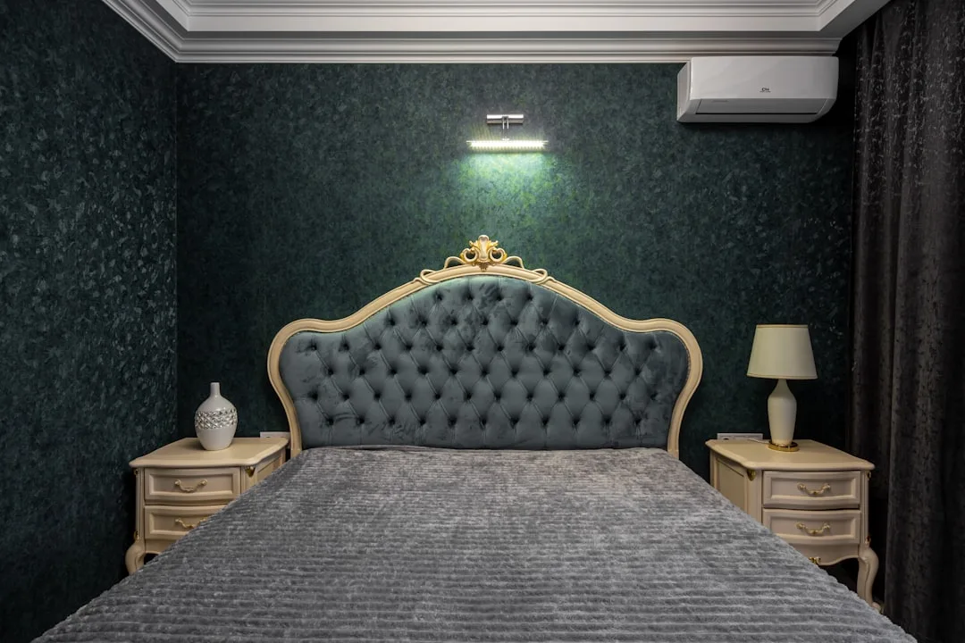 Luxurious bedroom with gray tufted velvet headboard, gray chenille bedspread, and dark green textured wallpaper