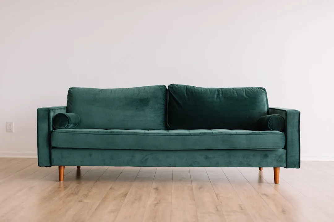 Teal velvet mid-century modern sofa on light hardwood floor against white wall illustrating the 2/3 sofa sizing rule
