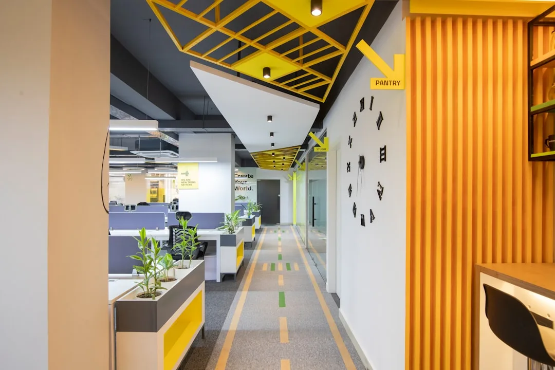 Modern office interior with yellow and gray 70/30 color scheme featuring workstations, decorative ceiling grid, and wall
