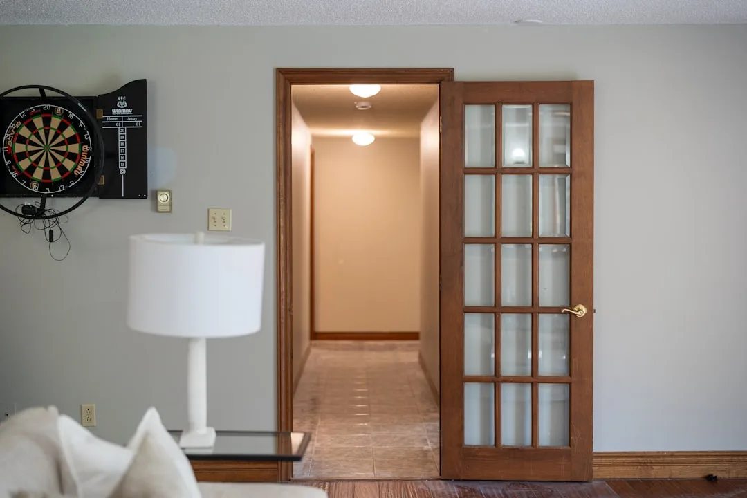 Basement game room with dartboard and French door leading to hallway, showing functional basement layout ideas