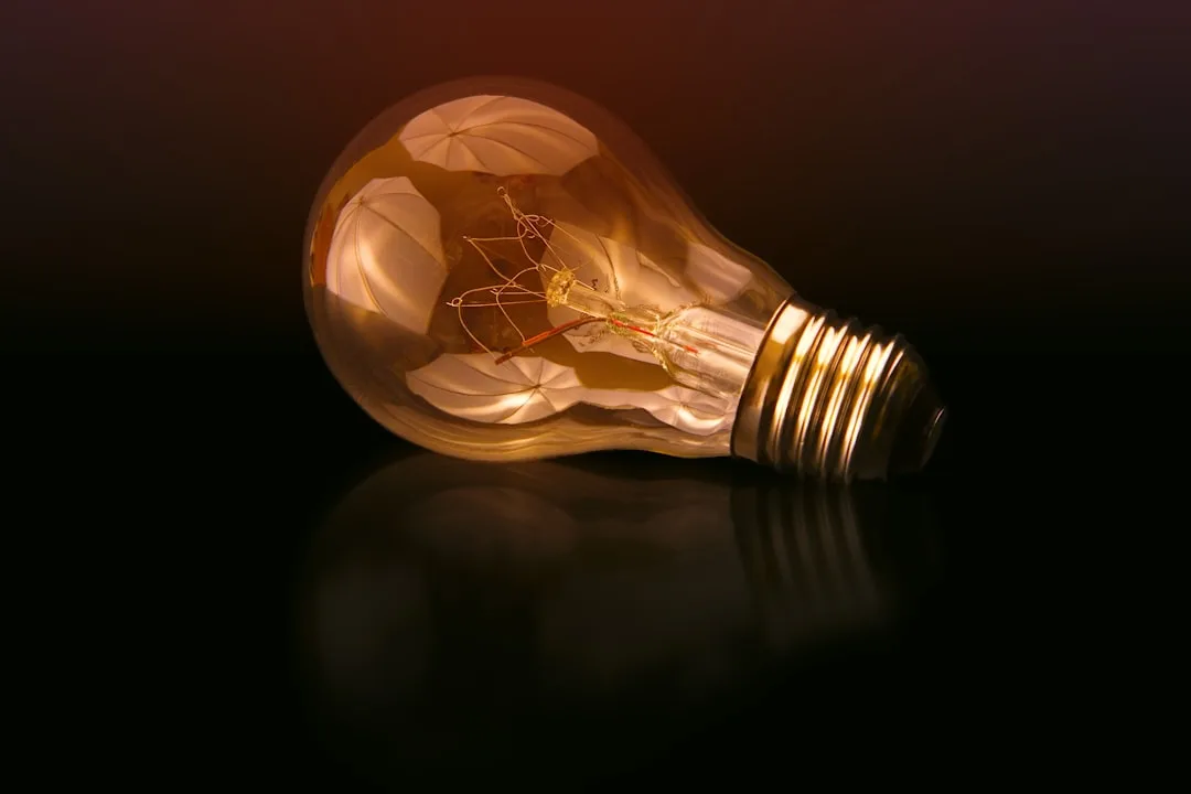Close-up of a vintage incandescent light bulb lying on its side with warm glowing filament on dark background