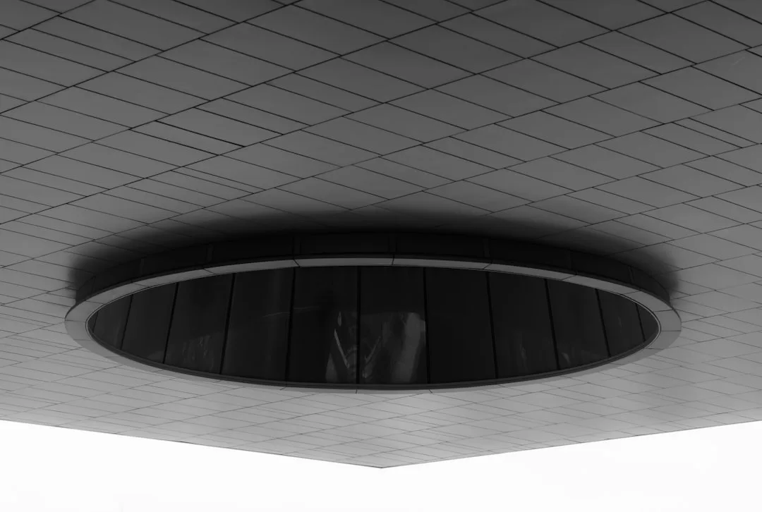 Modern architectural ceiling with circular recessed glass skylight feature in black and white tiled panel ceiling