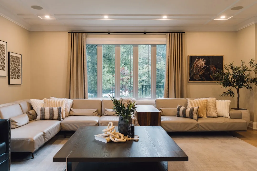 Two facing beige leather sofas with dark wood coffee table centerpiece in elegant neutral living room