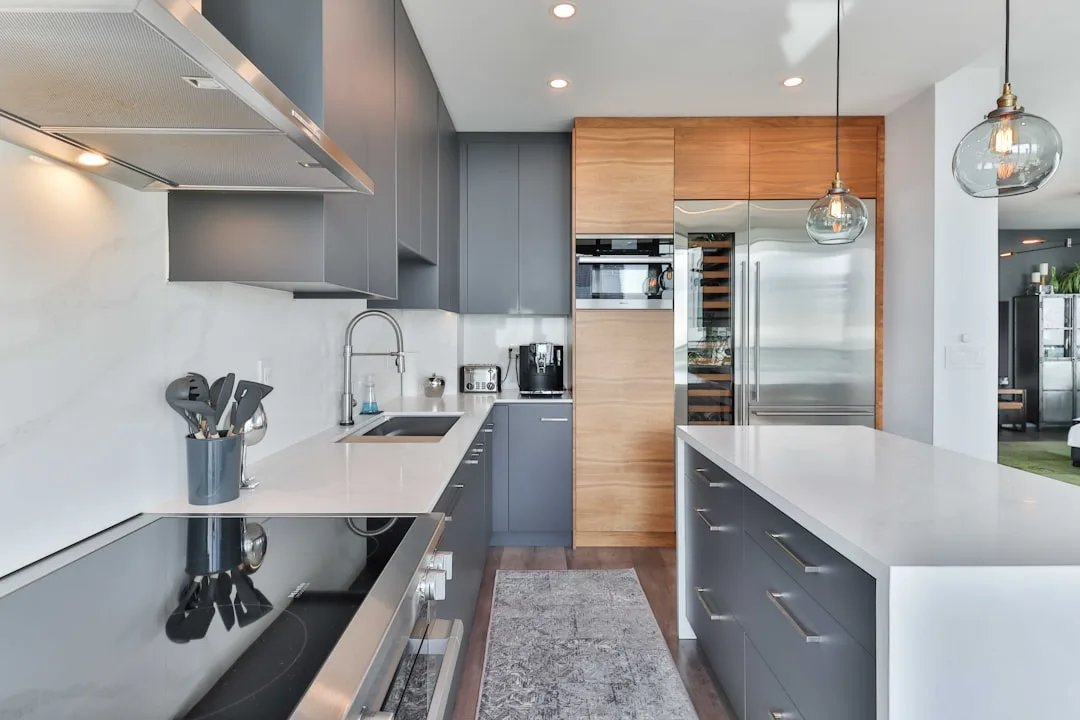 Modern kitchen with gray flat-front cabinets, white quartz countertops, and warm wood accent cabinetry pairing