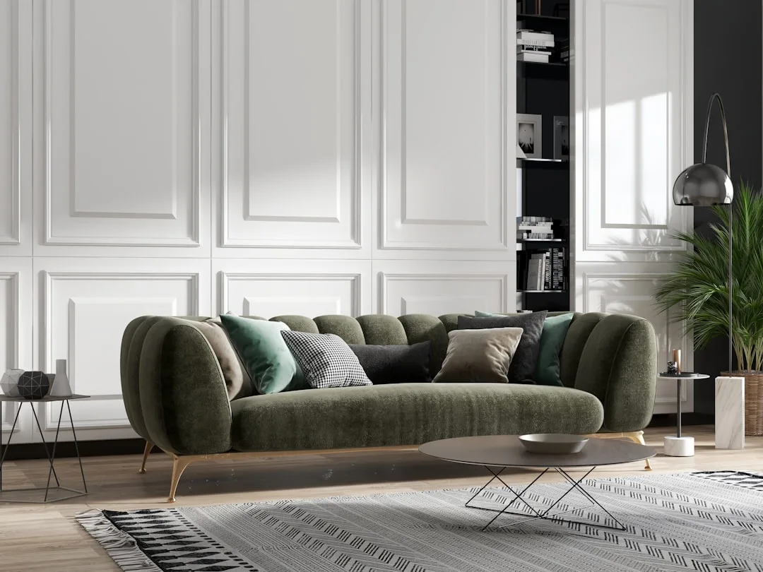 Dark green velvet curved sofa with decorative pillows in a modern white paneled living room