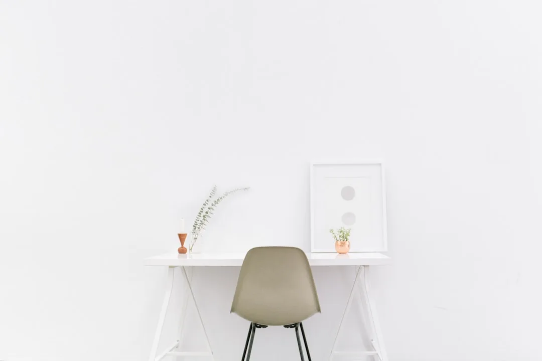 Minimalist white floating desk with Eames chair, small plant and framed art — modern home office setup