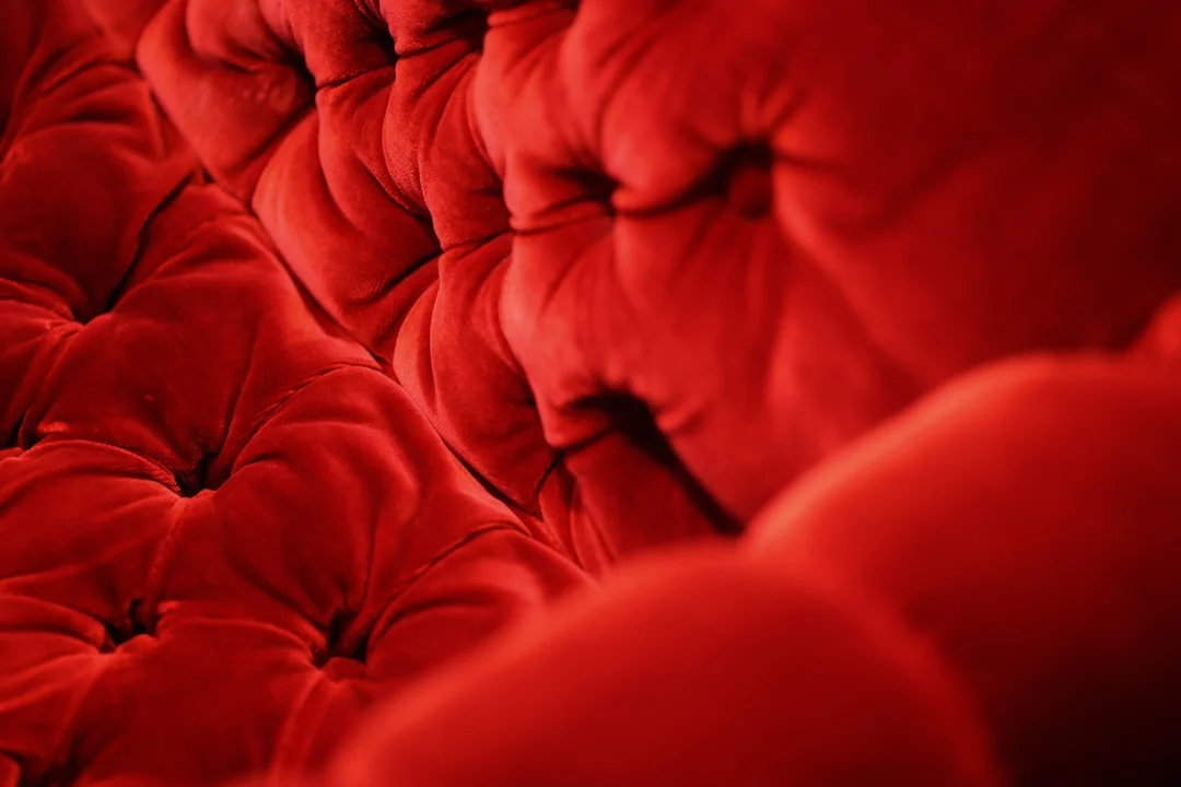 Tufted red velvet sofa close-up showing luxurious button detailing and fabric texture