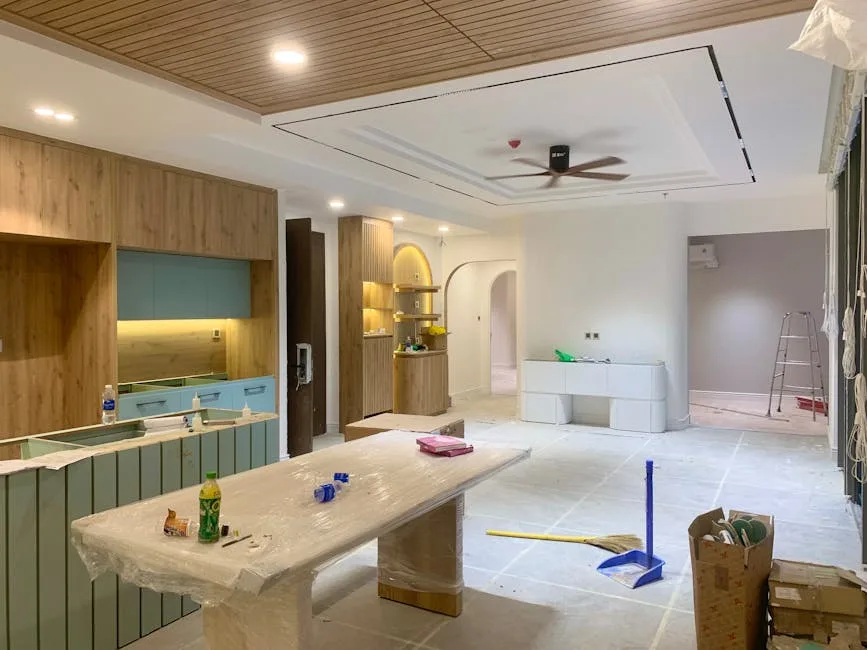 Open concept kitchen and living space under renovation showing wood ceiling, teal cabinetry, and intentional finish sele