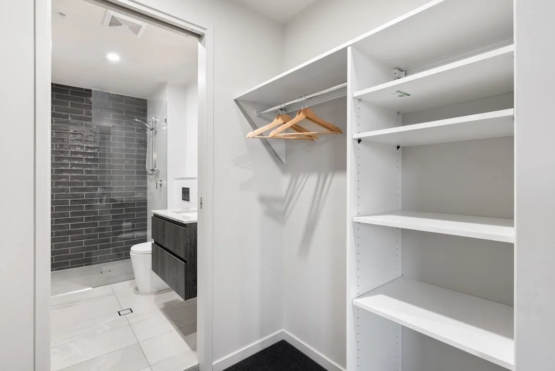 Walk-in wardrobe adjacent to open ensuite bathroom showing steam migration risk between wet and dry zones