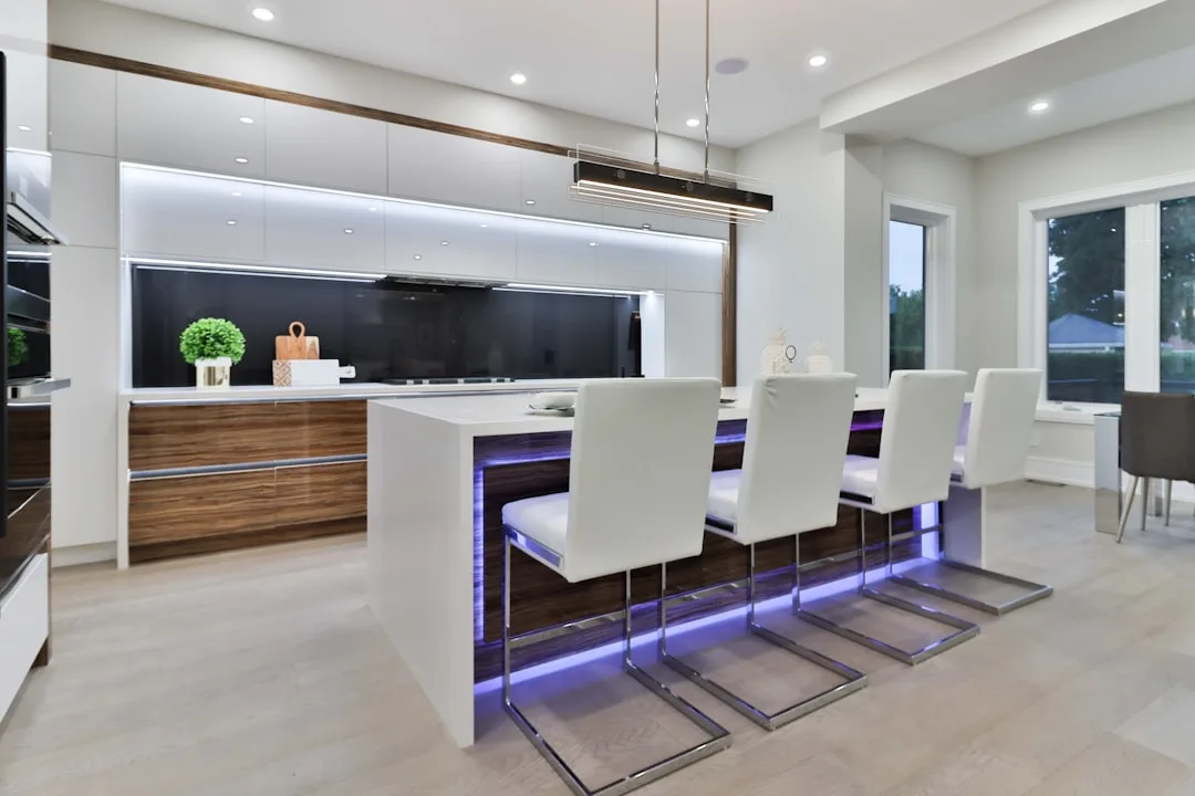 Modern kitchen island with purple LED underlighting and white bar stools showing 42-inch aisle clearance design
