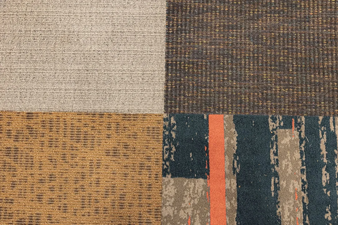 Four carpet tile samples showing contrasting textures: cream loop, dark brown tweed, golden sisal weave, and teal distre