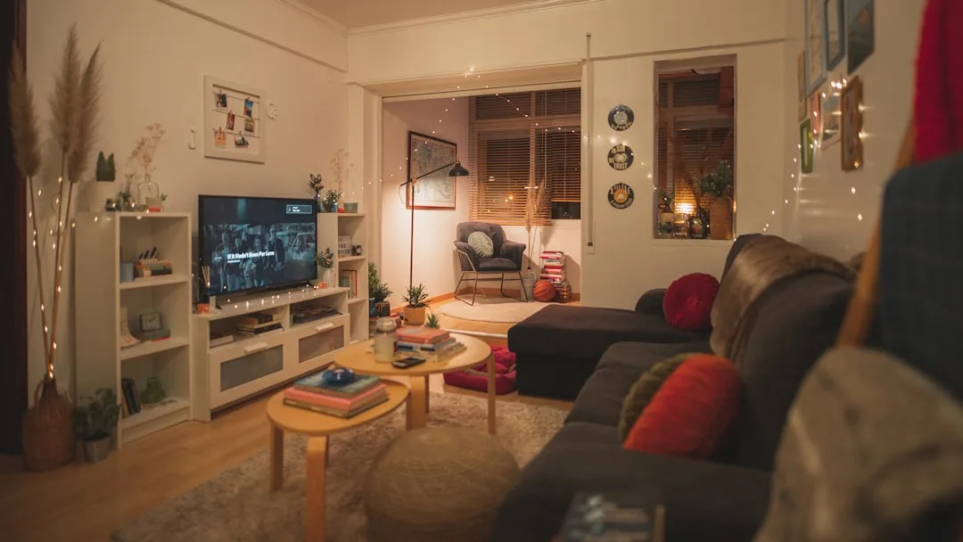 Cozy living room with warm fairy lights, dark sofa, TV unit, and layered ambient lighting creating visual clutter