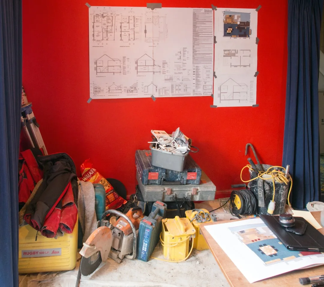Construction site with power tools, blueprints on red wall, and contractor equipment representing hidden renovation cost