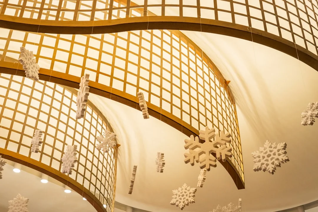White snowflake Christmas decorations hanging from ceiling in indoor atrium with warm golden lattice architecture
