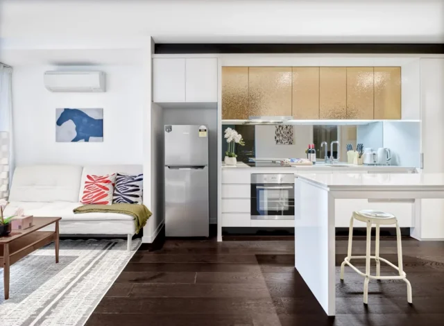 Modern open-plan kitchen with white cabinets, gold