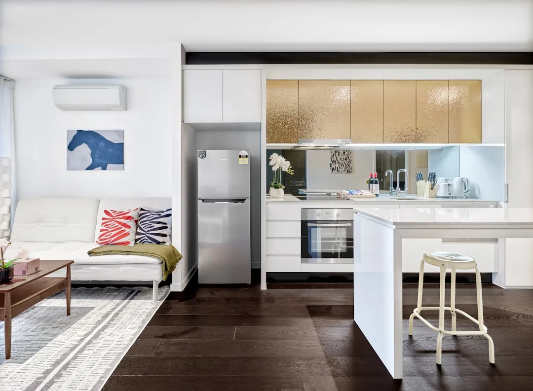 Modern open-plan kitchen with white cabinets, gold