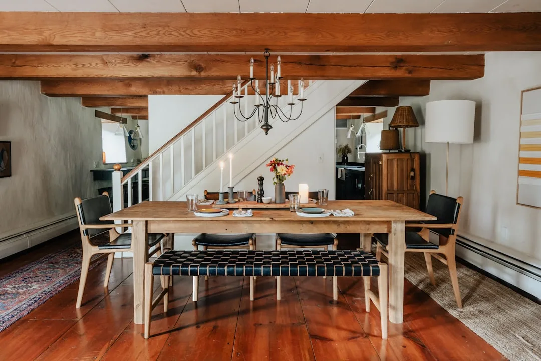 Farmhouse dining room with wrought iron candle chandelier, exposed wood beams, and rustic table setting with candlelight