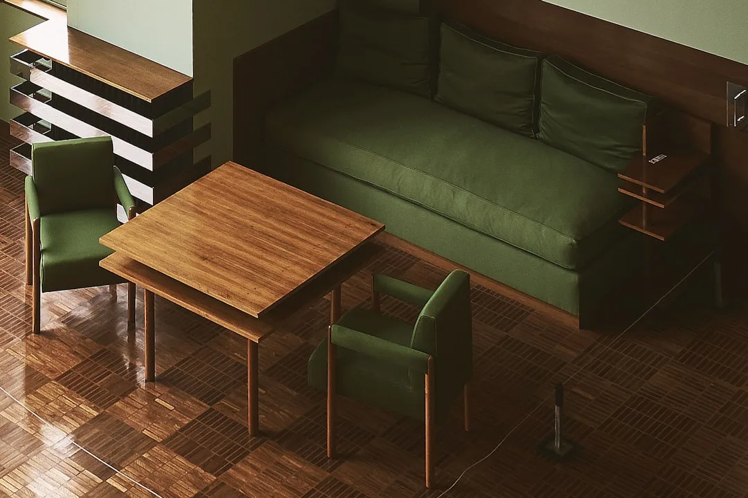Green upholstered sofa and armchairs arranged around wooden coffee tables on parquet flooring in small apartment