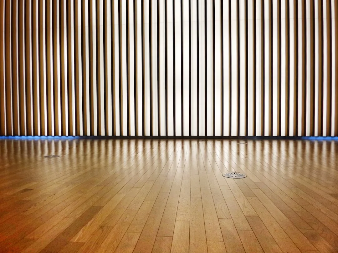 Floor-to-ceiling vertical wooden slat wall panels in a modern interior with polished hardwood floors
