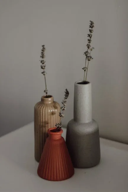 Three ceramic vases in neutral tones with dried lavender stems styled on a white surface for minimalist decor