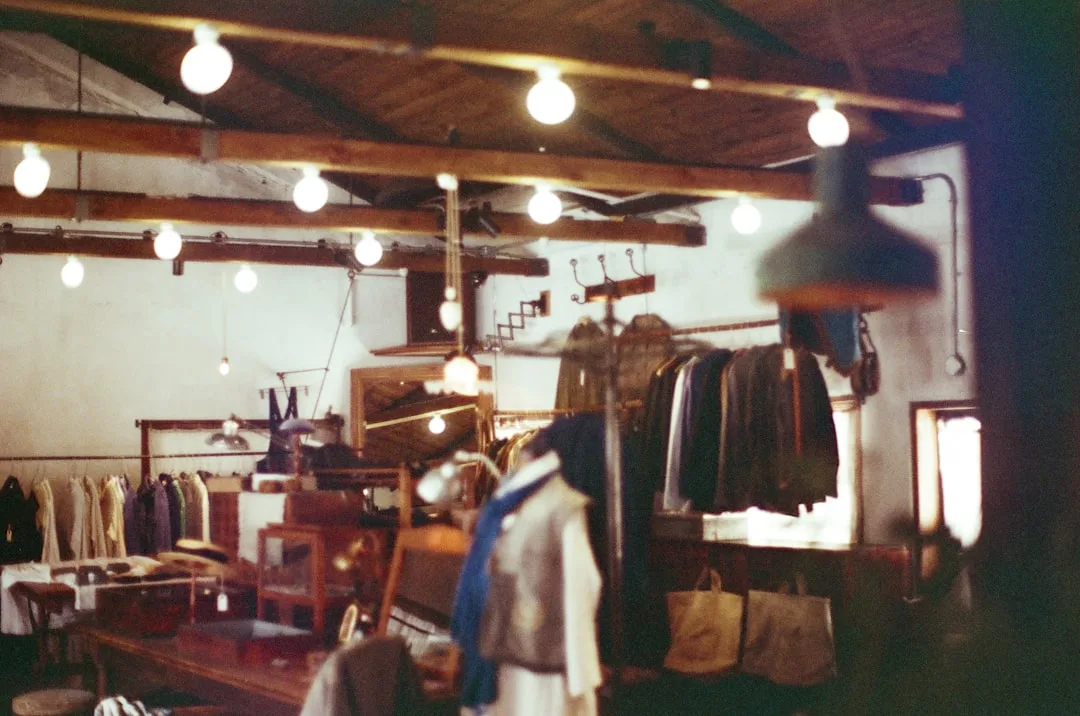 Vintage thrift store interior with hanging clothes racks, Edison bulb string lights, and rustic wooden beams
