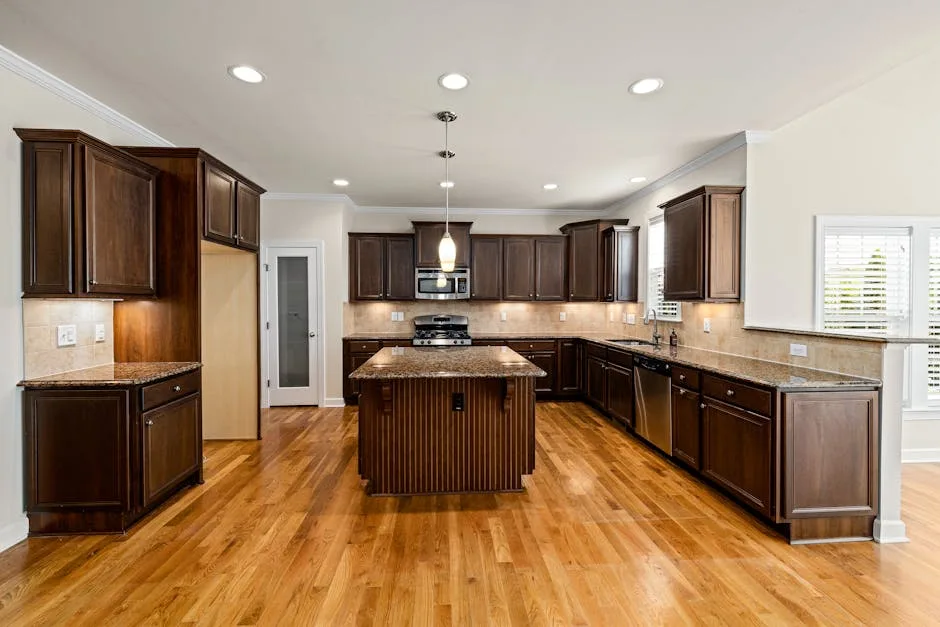 Dark wood kitchen with recessed ceiling lights and center island showing shadow-prone work surfaces without task lightin