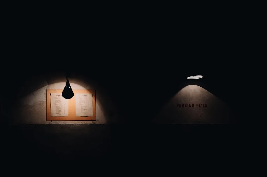 Dramatic low-lumen warm lighting illuminating a menu board and wall sign in a dark restaurant interior