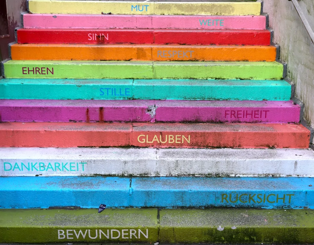 Colorful painted staircase steps in rainbow hues illustrating undertone mapping with German words on each step