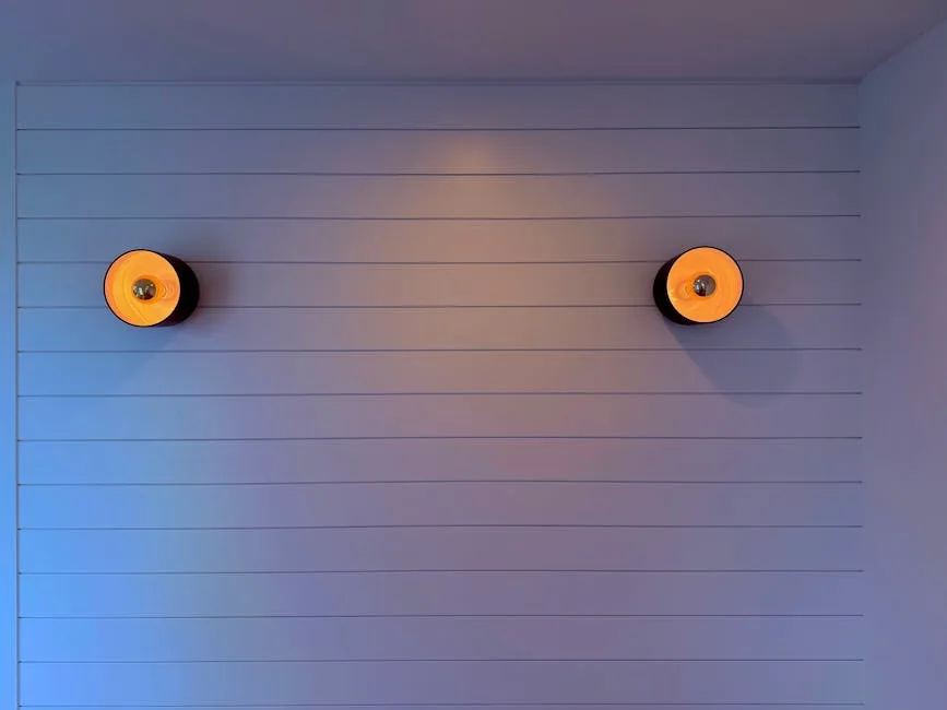 Two orange wall sconces mounted symmetrically on a white horizontal paneled wall demonstrating grazing light technique