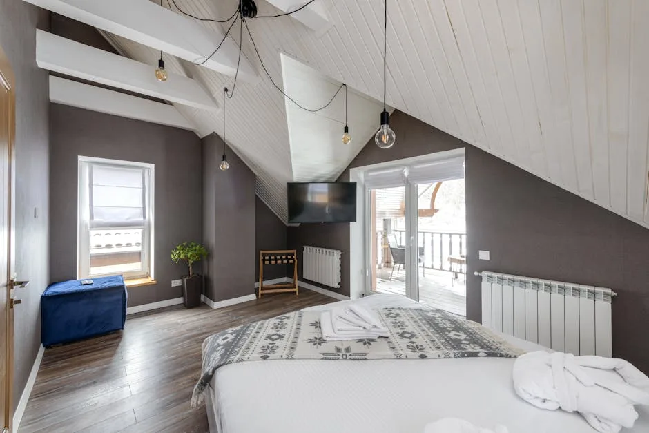 Attic bedroom with vaulted white ceiling, pendant Edison bulbs, and hardwood floors showing ceiling height impact on lig