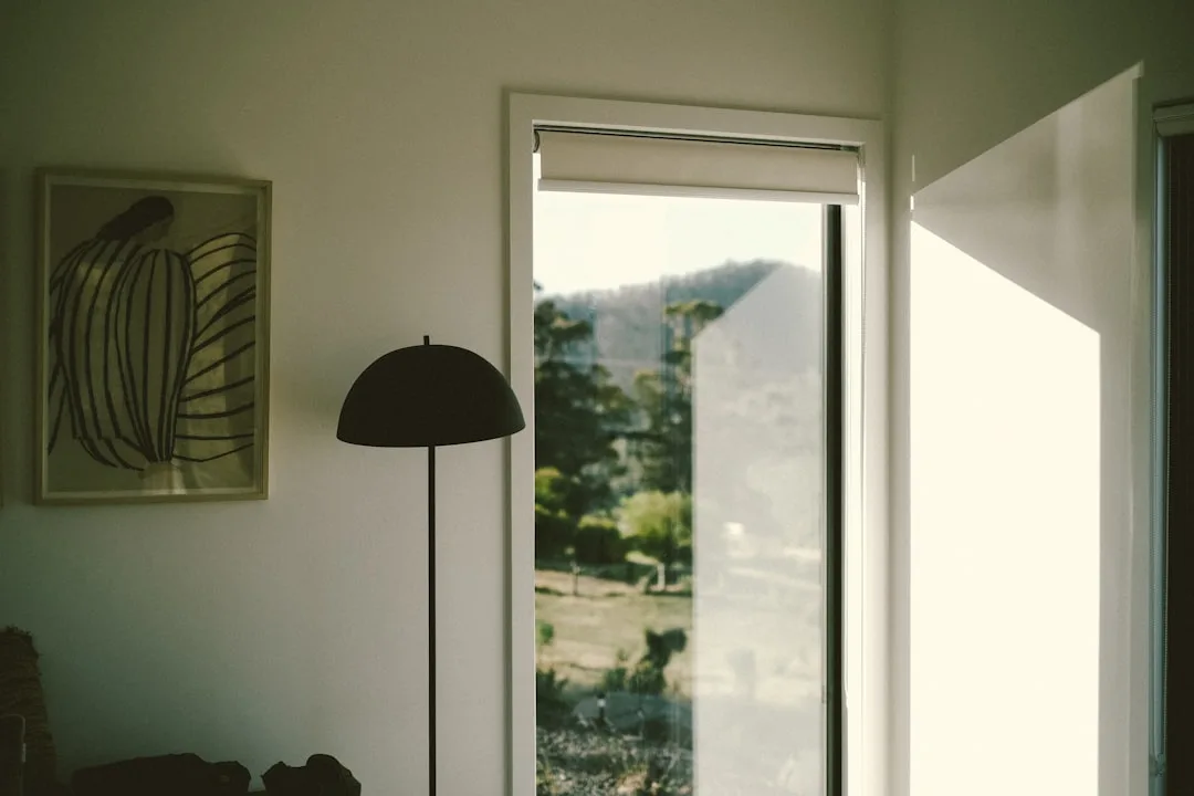 Interior room with open door alternative view showing window light, floor lamp and wall art in modern minimalist home