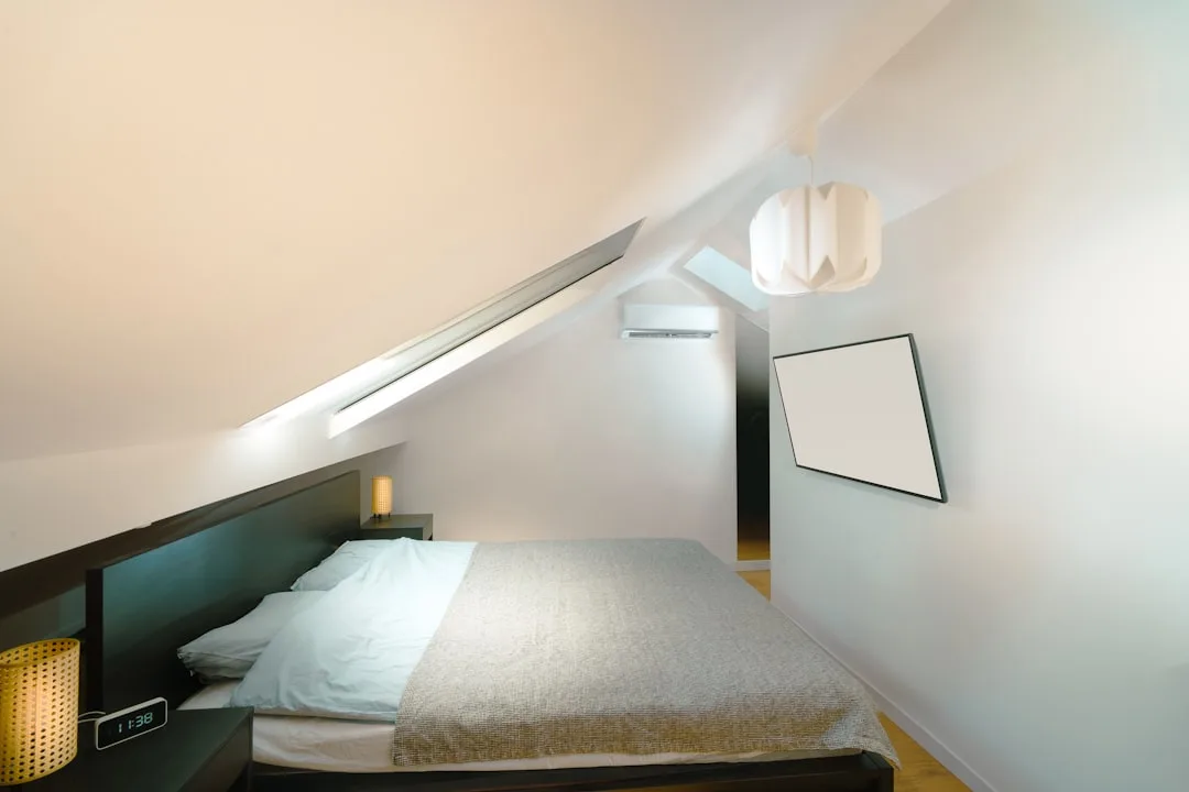 Finished attic bedroom conversion with sloped ceiling, skylight, double bed, pendant light and mini-split AC unit