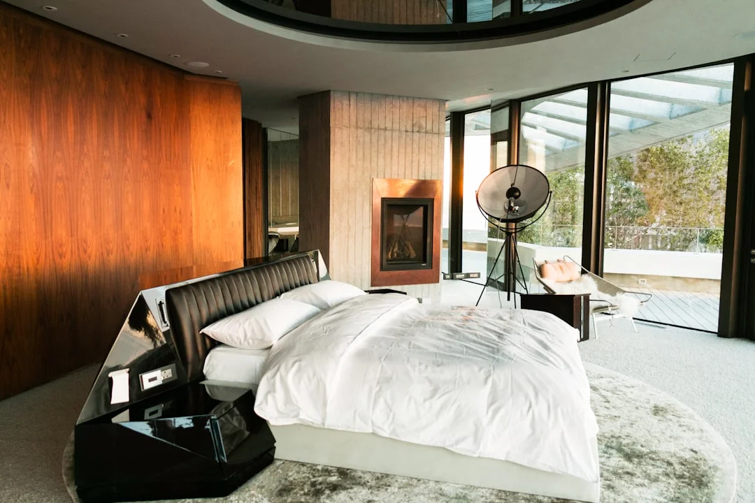 Luxury bedroom with white bedding layers on platform bed with fireplace and wood walls