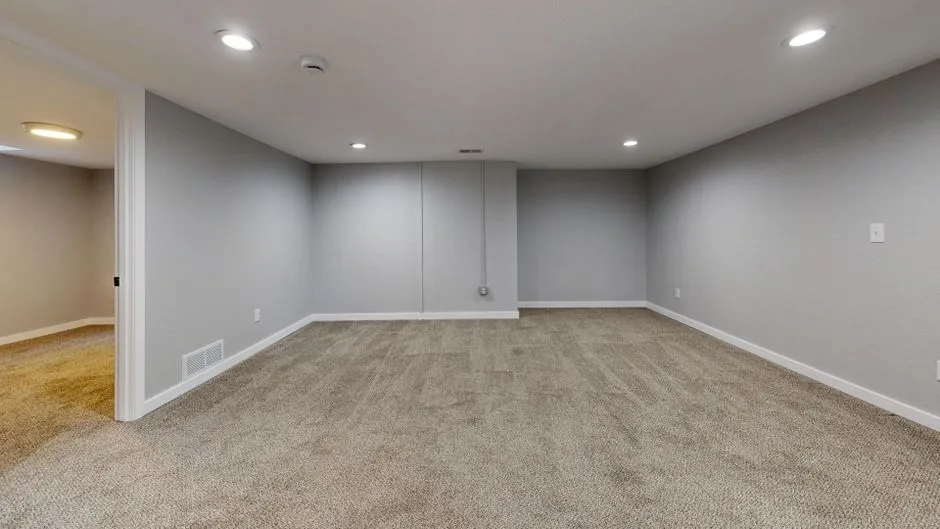 Empty finished basement with gray walls, recessed