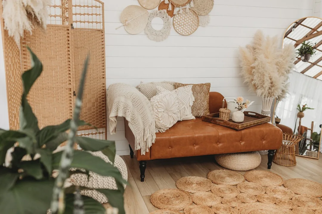 Boho farmhouse living room with tufted leather ottoman, macrame wall decor, rattan accents and pampas grass