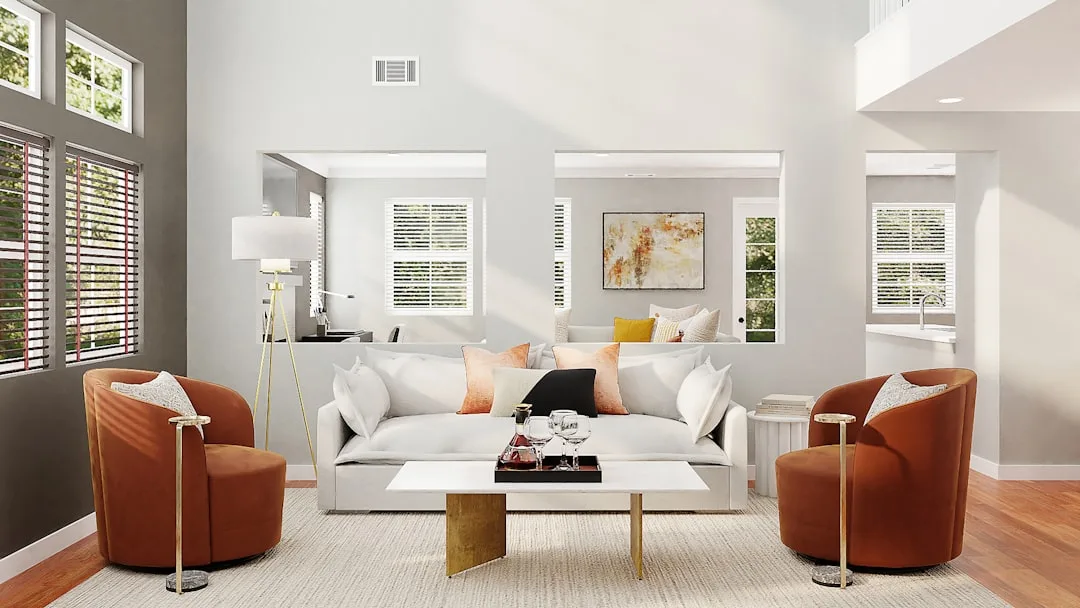 Modern living room with white sofa, orange accent chairs and gold coffee table illustrating home remodeling budget plann