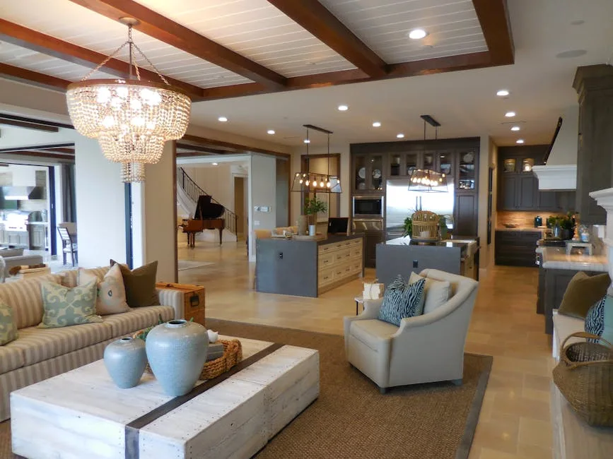 Open-concept transitional living room with beamed ceiling, crystal chandelier, neutral tones replacing farmhouse style