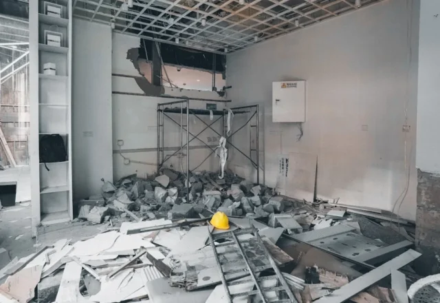 Interior room demolished with debris, rubble, scaf