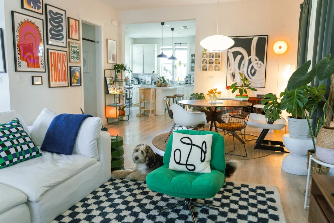 Eclectic living room with bold checkered rug, green chair, gallery wall and open plan dining area