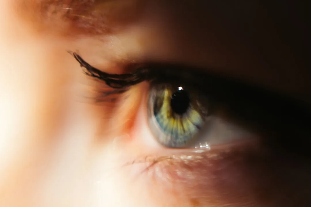Extreme macro close-up of a human eye with blue-green iris illustrating how eyes perceive warm and cool light