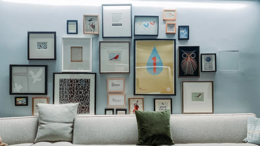 Gallery wall with eclectic framed art above grey sofa in studio apartment living space