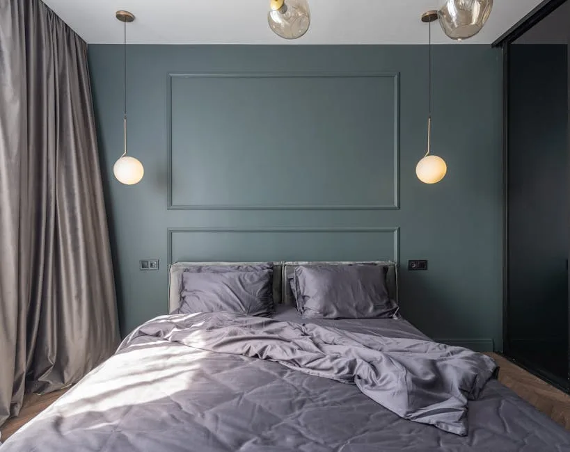 Primary bedroom with bed centered against teal wall facing doorway, flanked by globe pendant lights