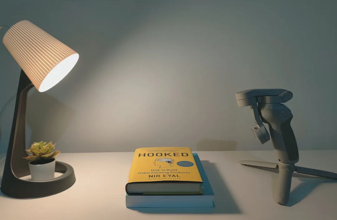 Budget desk lamp with striped shade illuminating a white desk with books and small succulent plant